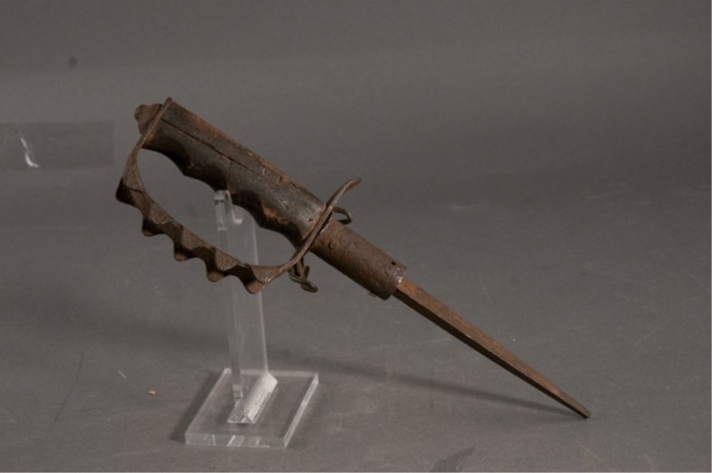 WWI Trench Knife: Relic condition. Triangular Blade. Unmarked blade has broken tip. Iron knuckle guard is heavily pitted. Remnants of scabbard. Blade: 8" Overall: 13 1/2"