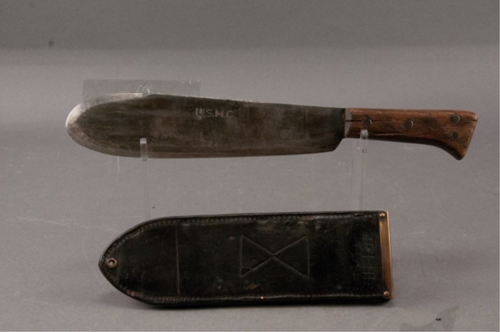 Model 1942 USMC Bolo Machete: With 1942 dated scabbard. Blade is grey with heavy sharpening. Grip is cracked. Scabbard shows heavy wear. Designs and name cut into leather. Blade: 11"
