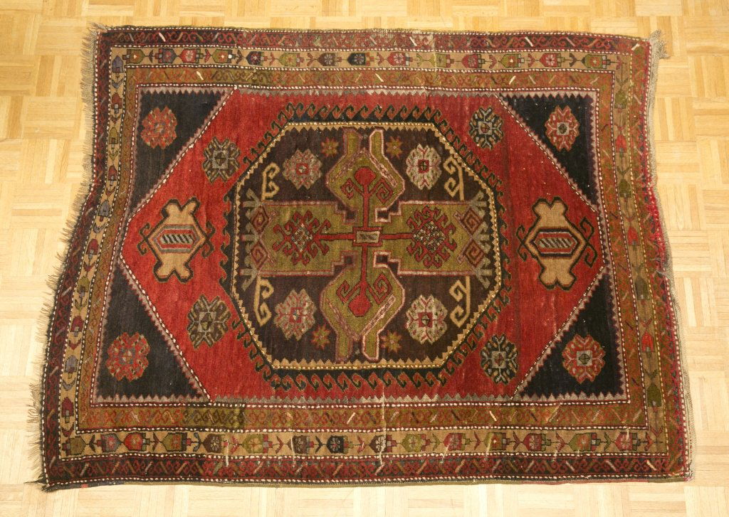 Semi-Antique Tribal Carpet: Red field with brown and green accents. Purchased in the town of Ursa, Turkey on the Aegean Sea coast. 5'11" x 4'8" Provenance: The Collection of The Baroness von Kuenheim of East Prussia