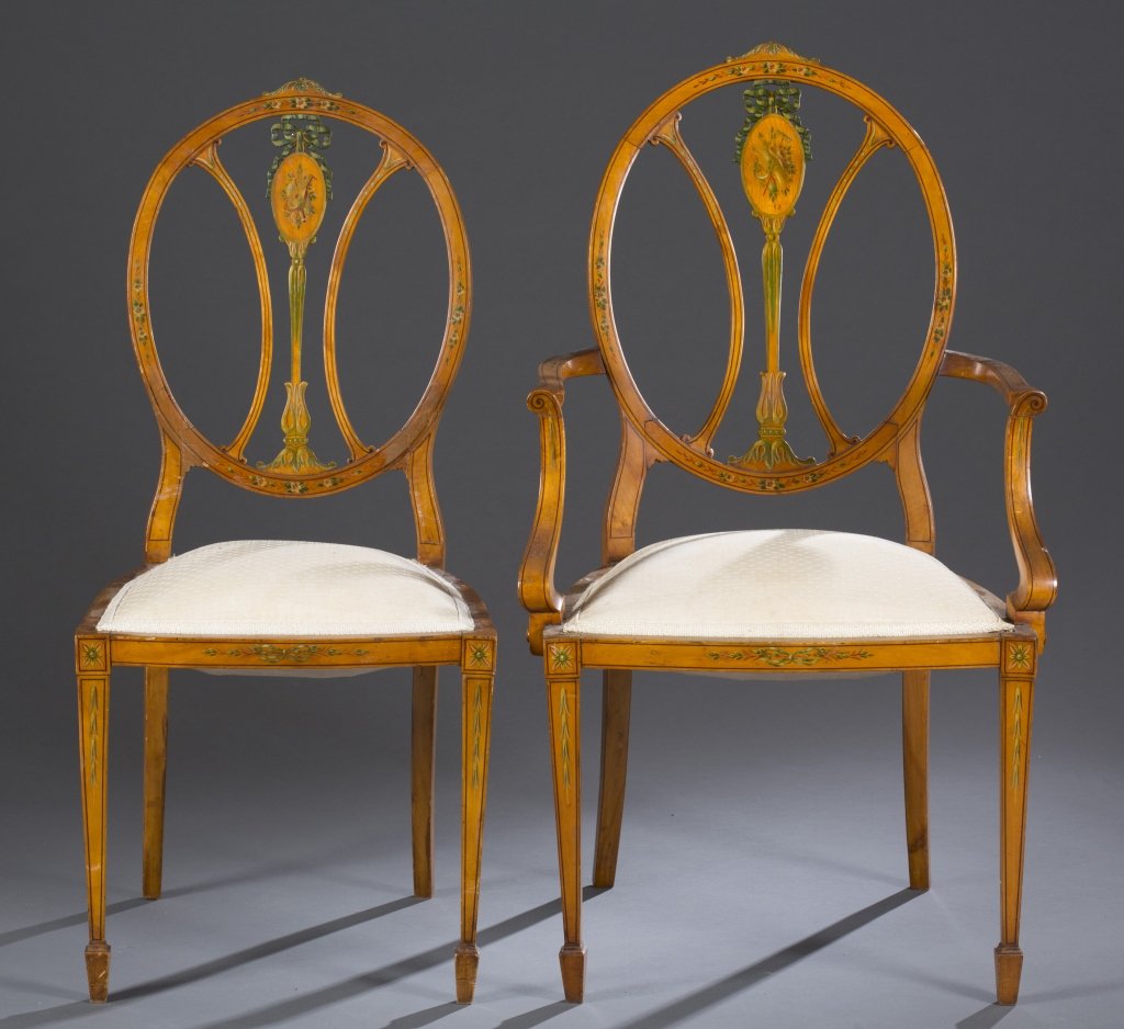 Set of Ten Edwardian Painted Dining Chairs: Ca. 1900. Floral painted crest with carved and painted bow-shape splat above oval decorated with oboe, arrows and horn. Repeated motif painted on seat rail. Straight tapered legs resting on spade feet