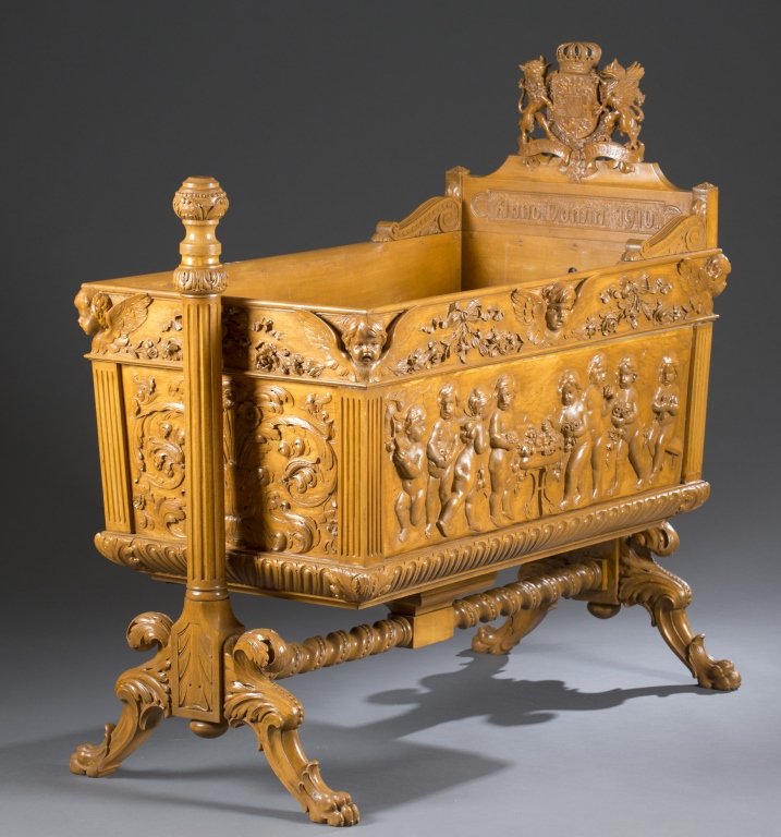 Ca. 1902 German Carved Giltwood Cradle: Carved and signed by D. Michaelsen, Schwerin. The headboard with crowned coat of arms of the Mecklenburg-Strelitz family, above a panel carved with ANNO DOMINI 1910, the frieze with winged cherub mask