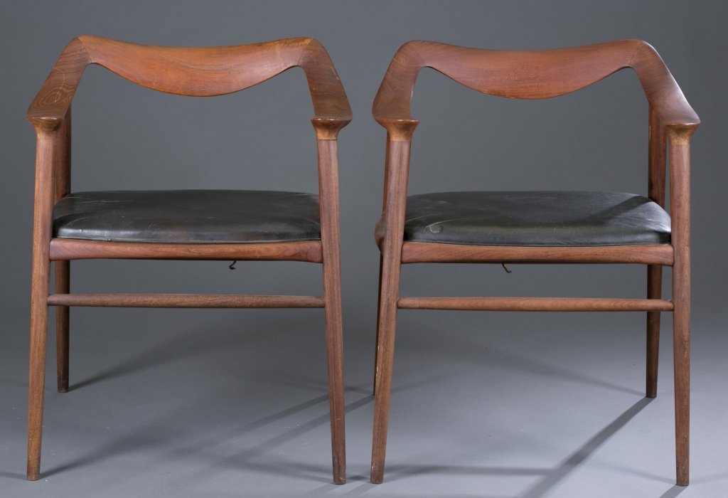 Pair of Norwegian Peter Wessel Style Armchairs: Teak frame with black leather seats. Underside of seat marked, "Made in Norway" 29" H x 24" W x 18" D Condition: One chair is missing one seat rail and small corner of crest is broken but piece is pre