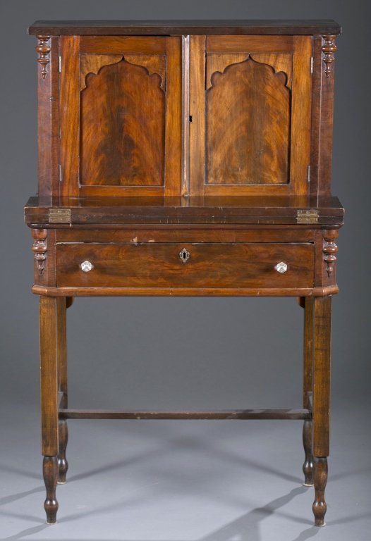 Early 20th c. English Diminutive Cabinet Desk: Mahogany with flame veneers. Gothic panels, glass pulls. 49 1/2" H x 30 1/2" L 23" D