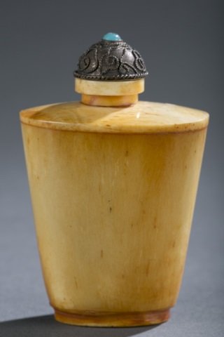 Bone Snuff Bottle: Unmarked bone bottle with tin stopper attached to tiny scoop with paste stone on top of stopper. 3" H x 2" L x 1 1/2" W. Signs of patina on stopper.