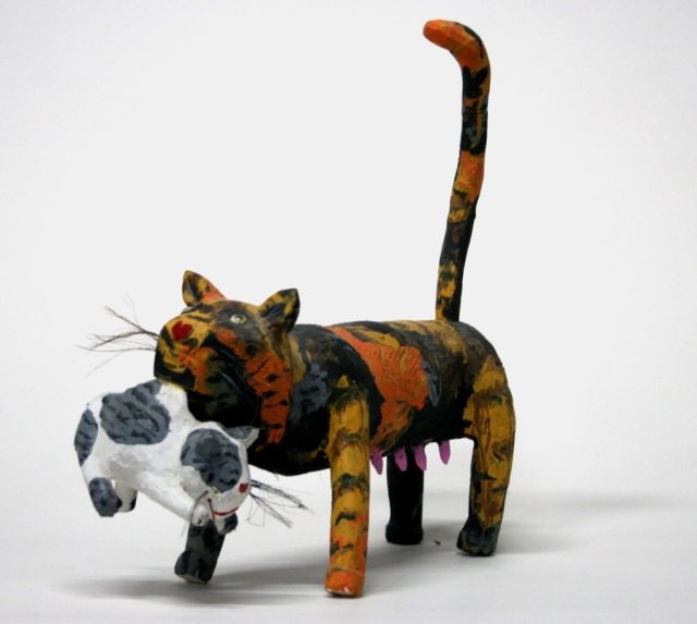 Miguel Rodriguez Carved Wooden Cat Sculpture.: New Mexican folk art carved wooden and polychrome painted cat carrying a kitten. On bottom of kitten, signed Miguel Rodriguez and dated 2000. 19"h x 16"l x 7"w.