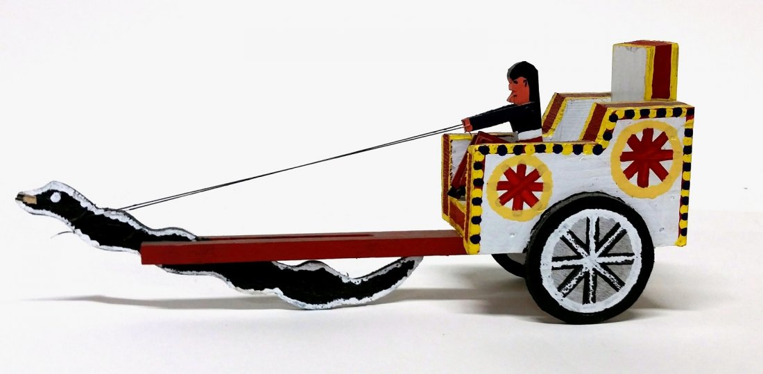 James Harold Jennings (North Carolina, 1931-1999).: A folk art polychrome painted wood sculpture of a Native American man driving a chariot pulled by a serpent. On bottom, signed by artist. 6 1/4"h x 3 3/4"w x 14 3/4"l.