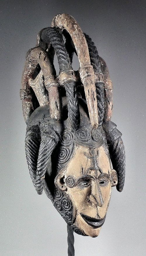 A Fulani Mask (Nigeria) - Carved hardwood mask dec: A Fulani Mask (Nigeria) - Carved hardwood mask decorated with black and white pigment and with bold braided crown, with elongated nose and carved lizard to forehead, 19.5ins high