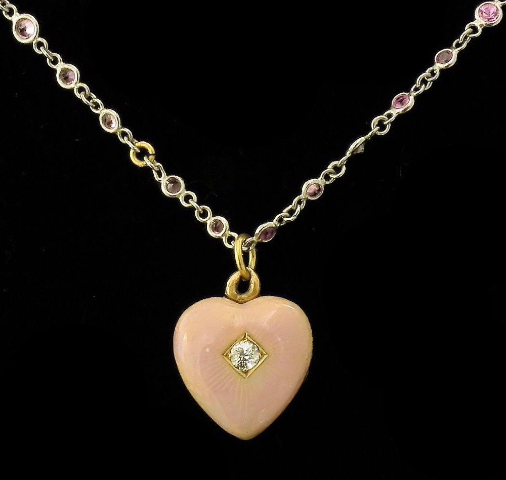 A late 19th Century gold coloured metal enamel and diam: A late 19th Century gold coloured metal enamel and diamond set heart pattern pendant locket, the face set with a small rose diamond within pale pink guilloche enamel borders, 15mm x 18mm overall, susp