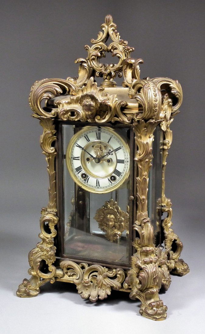 A late 19th/early 20th Century American gilt brass case: A late 19th/early 20th Century American gilt brass cased "Four Glass" mantel clock by The Ansonia Clock Company, the 4ins diameter dial with Roman numerals and visible escapement to the eight day two