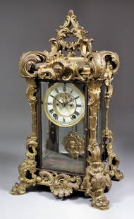 A late 19th/early 20th Century American gilt brass case: A late 19th/early 20th Century American gilt brass cased "Four Glass" mantel clock by The Ansonia Clock Company, the 4ins diameter dial with Roman numerals and visible escapement to the eight day two
