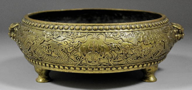 A Chinese bronze two-handled bowl cast with dragons cha: A Chinese bronze two-handled bowl cast with dragons chasing the Sacred Pearl, 9.75ins (248mm) diameter x 3.75ins (95mm) high (cast six character mark - polished)