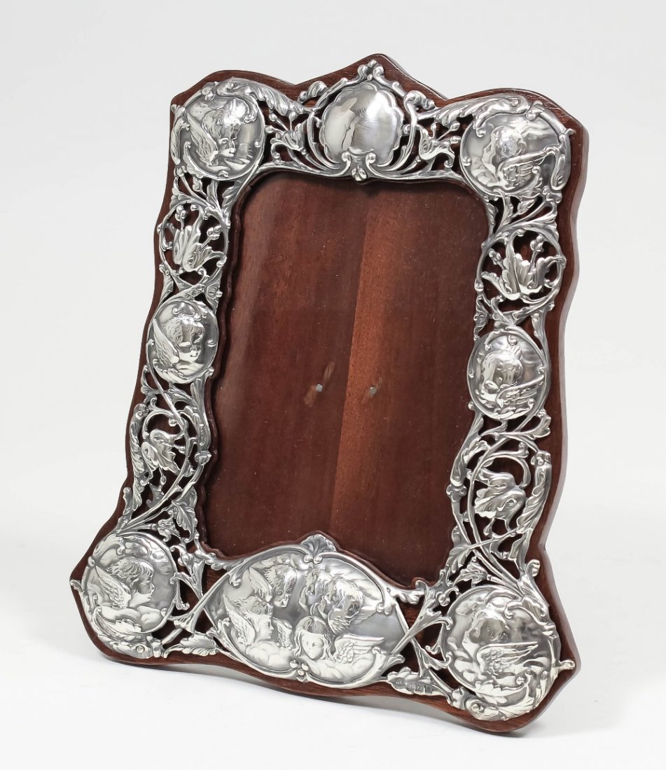 An Edward VII silver rectangular photograph frame, the : An Edward VII silver rectangular photograph frame, the pierced rectangular border embossed with cupids, 8.5ins x 7.5ins (to hold picture 6ins x 4ins), by William Comyns, London, 1903 (with replaced ma
