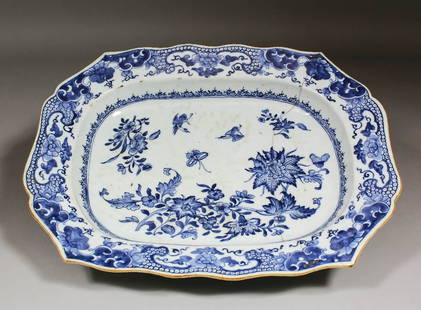 A Chinese blue and white porcelain meat plate of shaped: A Chinese blue and white porcelain meat plate of shaped outline, painted with flowering sprays, birds and moths within a stylised border, 12.25ins (311mm) x 15.75ins (400mm) (18th Century - cracked