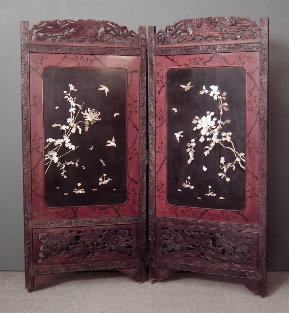A Japanese carved and stained hardwood two fold draught: A Japanese carved and stained hardwood two fold draught screen inset with cinnabar and black lacquer shibyama panels decorated with birds and flowers, each fold 72ins (1829mm) x 33ins (838mm) (early 2
