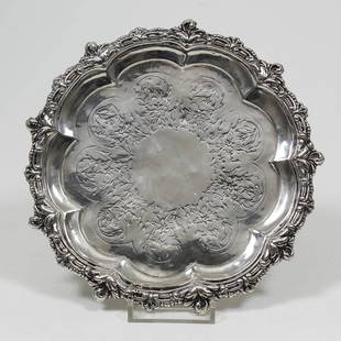 A George III silver circular waiter with shaped and: A George III silver circular waiter with shaped and leaf moulded piecrust rim, engraved to centre with leaf scrolls, on three splayed panel feet, 7ins diameter, London 1795 (weight 10ozs)