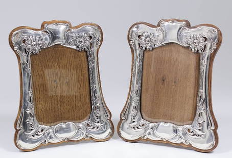 A matched pair of Edward VII silver photograph frames: A matched pair of Edward VII silver photograph frames of shaped outline and of Art Nouveau design with pierced floral and leaf borders, 8.5ins x 7ins (to take pictures 5.5ins x 4ins), by Henry