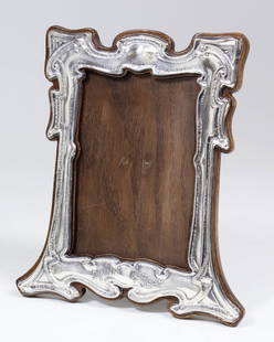 An Edward VII silver rectangular photograph frame of: An Edward VII silver rectangular photograph frame of shaped outline and of Art Nouveau design, the apron embossed in relief and worded "Dinna Forget", 8.5ins x 7ins (to take picture 5.5ins x 4ins),