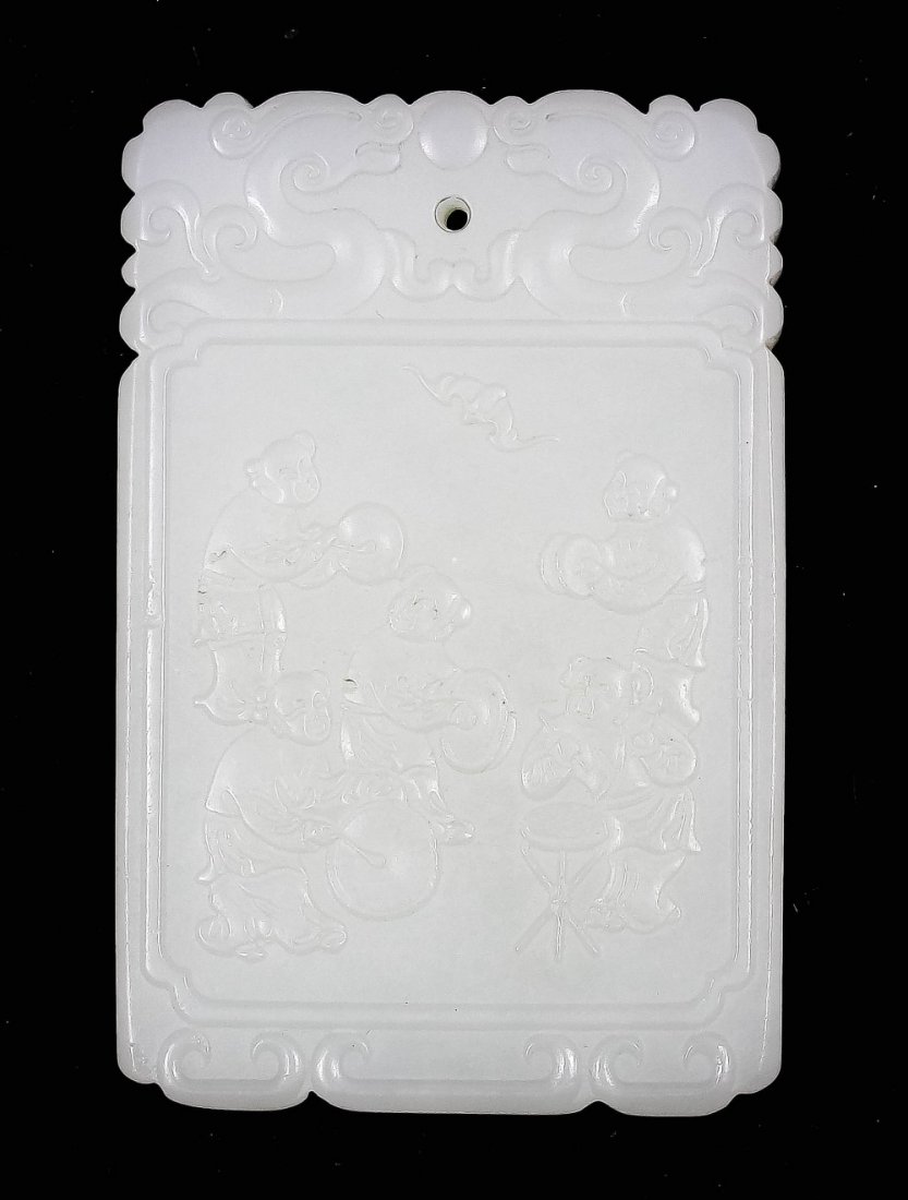 A Chinese pale celadon jade pendant carved with boys: A Chinese pale celadon jade pendant carved with boys playing musical instruments to one side, the other with a three line script, 2.25ins (57mm) x 1.5ins (38mm)