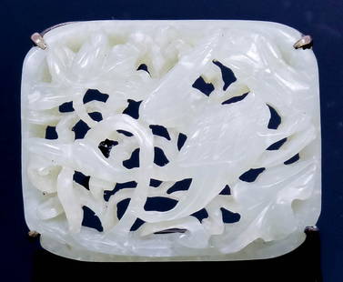 A Chinese celadon jade and metal mounted brooch pierced: A Chinese celadon jade and metal mounted brooch pierced and carved with a bird in flight, 1.5in (38mm) x 1.25in (31mm)
