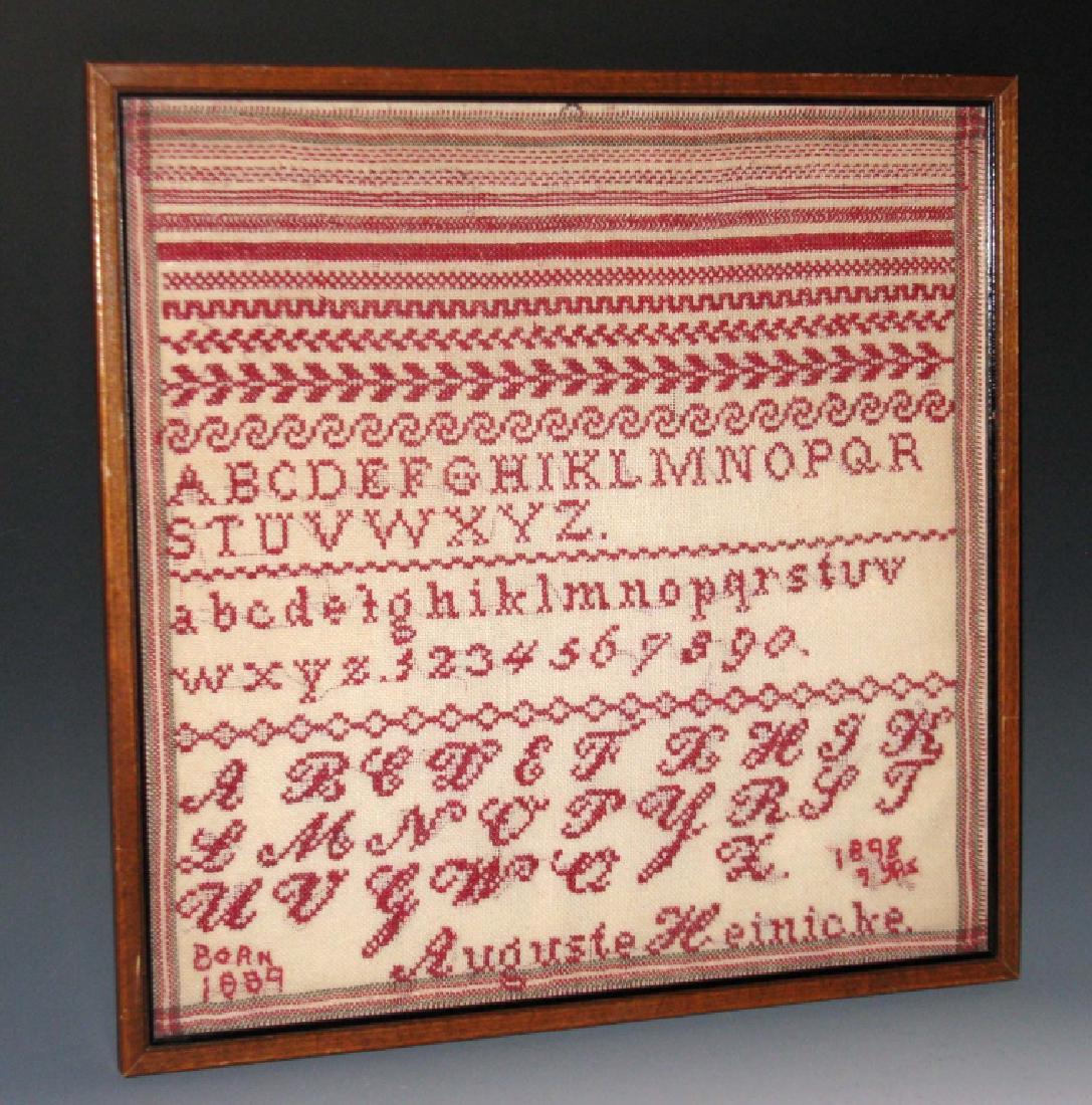 1898 CROSSSTICH SAMPLER BY AUGUSTE HEINICKE: 1898 CROSSSTICH SAMPLER: Auguste Heinicke was 9 years old when she completed this sampler in 1898 which includes the alphabet, numbers and border designs stitched in red cotton, on a cotton tea towel,
