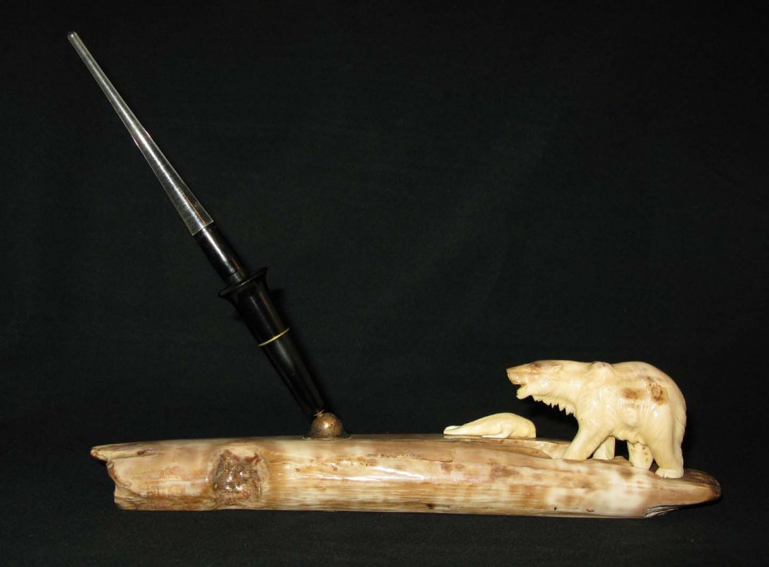 Albert Berry Carved Fossilized Bone Pen holder: Albert Berry Pen Holder; carved bone mounted to fossilized bone; Carved in the form of a polar bear standing over a seal. Carved walrus tusk 10"l. Bears Berrys' Arts & Crafts Shop label on base. Alber