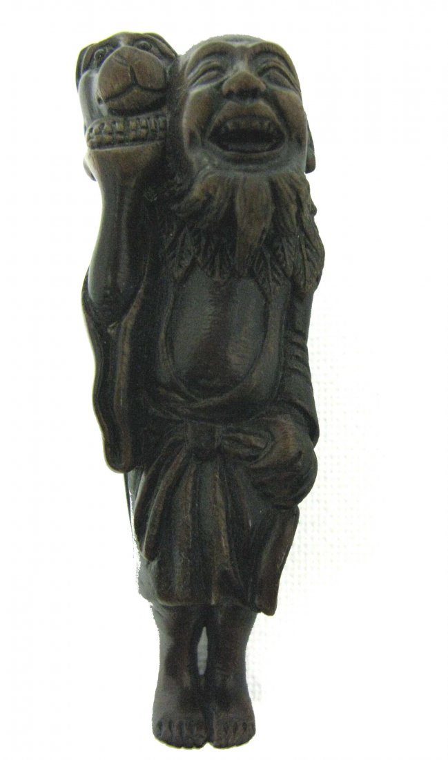Wood Netsuke Man and ShiShi or Foo Dog Signed: Carved wood netsuke with smiling man carrying shishi or Foo dog on his shoulders. 3.125" This piece is signed on a mother of pearl inset into the base of the foot.