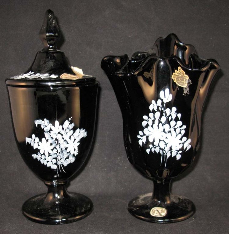 2 Pcs Black Fenton Glass Hand Painted with Daisies: Two pieces of Black Fenton Glass Hand Painted with Daisies both with Original Labels. 1 of 2: a shield shaped footed candy jar 9h, painted by Louise Piper. 2 of 2: Ruffled edge vase, 8"h, B. Lowers.