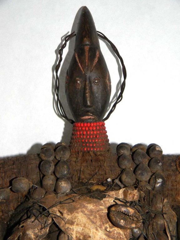 African Cameroon Namchi Fertility Fetish Doll: African Fertility doll from the Namchi people of Cameroon, comprised of carved wood adorned with hide, cowrie shells, glass beads, feathers, seeds and fetish bags, 21h.