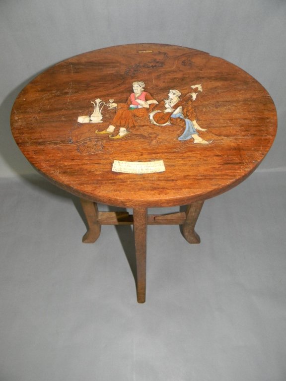 OMAR KHAYYAM RUBAIYAT BONE & WOOD INLAY TEA TABLE: Hardwood marquetry table with natural and dyed bone with wood depicting a lover's scene with verse from Omar Khayyam's Rubaiyat". The oval top measures 12 3/8" x 9 7/8" and rests on a collapsible base