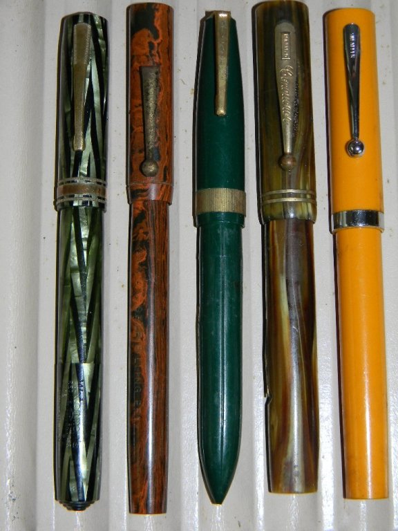 5 FOUNTAIN PENS:WATERMANS, PALMER 14K GOLD NIBS: Vintage Art Deco Era Fountain Pens: Waterman's Fountain Pen in Green Pearl Chevron Design, Schaefer Orange, Conqueror Faux Wood Pen, Advance Green Pen, Lewis's Faux Wood Grain Pen.