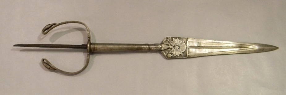 ANTIQUE UNUSUAL INDO-PERSIAN SPEAR TIP: ANTIQUE UNUSUAL INDO-PERSIAN SPEAR TIP, the straight blade with decoration of a blooming louts held in the jaws of a fiercely fine-toothed animal, round shaft with two bird terminals. 56.51cm (22 1/4"