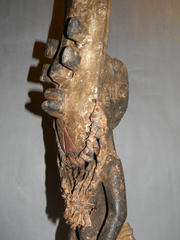 GREBO MASKED FIGURE LIBERIA & IVORY COAST AFRICA: GREBO MASKED FIGURE LIBERIA AFRICA; standing figure wearing Grebo mask with four tubular eyes, prominent lips and sloping nose, adorned with cloth, fiber, pigment and remnants of mounted feathers, 58.