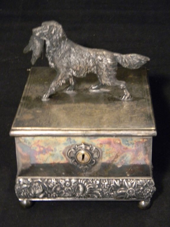 MERIDEN SILVERPLATE FIGURAL HUNTING DOG HUMIDOR: MERIDEN AMERICAN SILVERPLATE FIGURAL HUMIDOR: Rectangular box is raised upon four ball feet and decorated with engraved and repousse floral decoration. The hinged lid is surmounted by a hunting dog ho