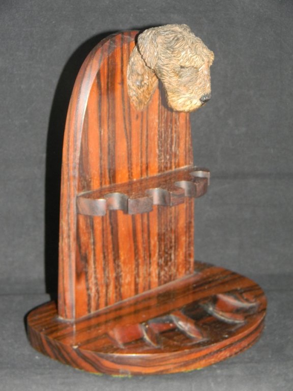 ALFRED DUNHILL CARVED DOG PIPE STAND: ALFRED DUNHILL CARVED DOG PIPE STAND: stand with wells for 4 pipes and with a carved wooden dog mount at the crest, Stamped "Alfred Dunhill", "Made in England" on the back, 8.5" h x 7.25" w.