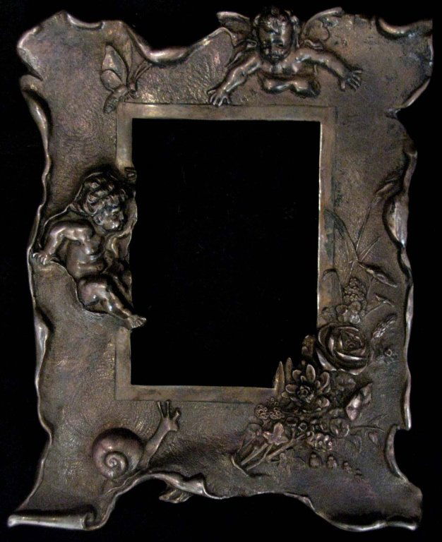ART NOUVEAU METAL FRAME WITH PUTTI, FLOWERS, SNAIL: ART NOUVEAU METAL FRAME: Naturalistically cast with putti and a bouquet of flowers coming through the frame and with a snail and bee perched at the edges, two circular rings on back for hanging, 10.25