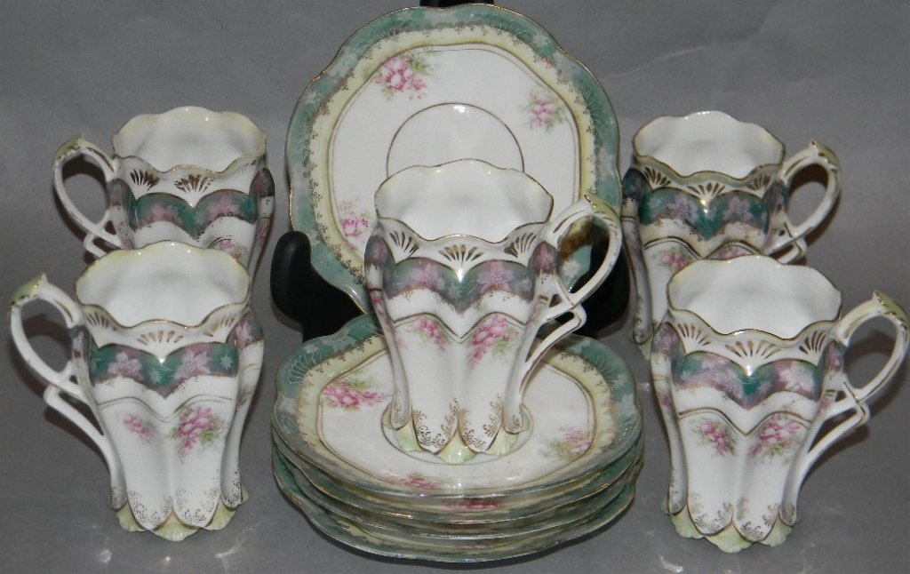 ART NOUVEAU PORCELAIN CHOCOLATE SERVICE: ART NOUVEAU PORCELAIN CHOCOLATE SERVICE: Cups and saucers for five all with floral sprays, gilded and luster decoration; the cups molded with wasted sides and sinuous foliate handles; c. 1890; probabl