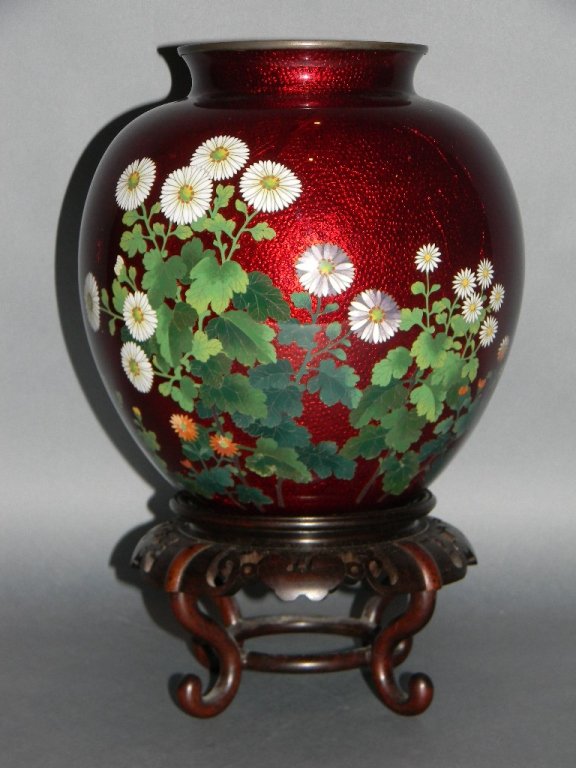 GINBARI JAPANESE CLOISONNE SIGNED VASE: Finely stippled and incised foil background with an overlay of vibrant pigeon blood red and enamel floral decorations, base impressed with unknown artist mark's. Vase rests upon carved and pierced har