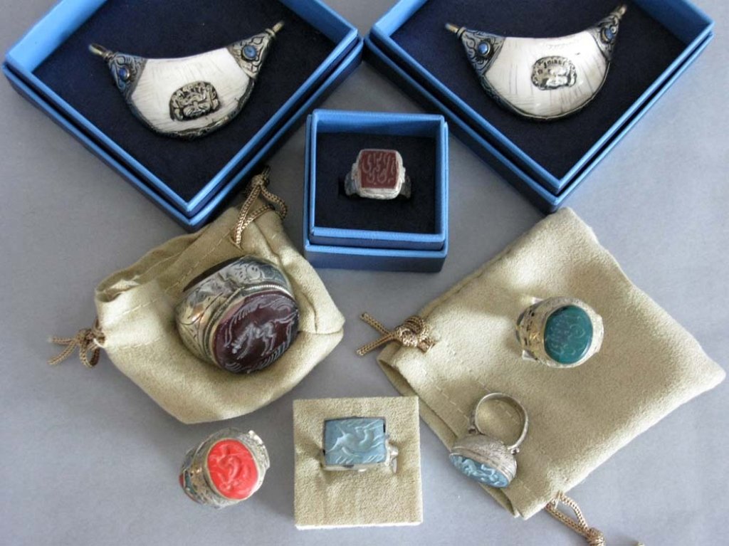 GROUP OF ISLAMIC HARDSTONE & CLAY INTAGLIO RINGS: A group of eight Islamic rings and pendants. The six rings set with intaglio carved stone, glass and ceramic panels, most depicting animals. The pendants with bone mounted in metal. age undetermined.
