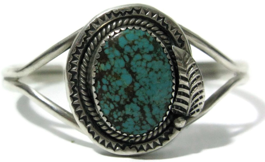 SIGNED NAVAJO STERLING CUFF BRACELET W/ TURQUOISE: SIGNED NAVAJO STERLING CUFF BRACELET W/ TURQUOISE: Navajo, Native American, early 20th c., central oval cabochon turquoise (20mm x 16mm) which is saw-tooth mounted to a hand stamped border which is ac
