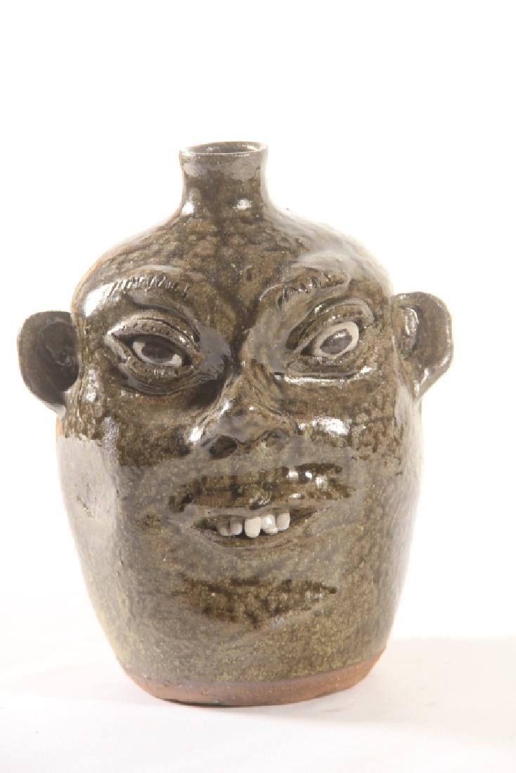 Southern Stoneware Face Jug: Dated 1985, by Cleater Meaders, Georgia. Nicely formed jug having white clay eyes and teeth with a runny alkaline glaze. Excellent condition. H9 1/2"