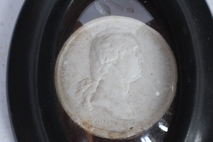Antique Mershome Pottery Intaglio Medallion: 19th century. White clay intaglio housed in oval frame with dome glass, Commission Americana Medallion. Some yellowing to edge of clay body and slight nicks consistent with age. H7" total size