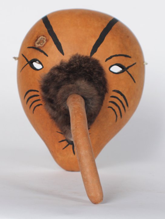 Cherokee Gourd Mask by Fred McCoy: Cherokee, North Carolina. Having an interesting form with long nose crafted from a gourd stem and painted facial features. Having the original artist tag at interior. H11 1/2" D13" Sold from the perso