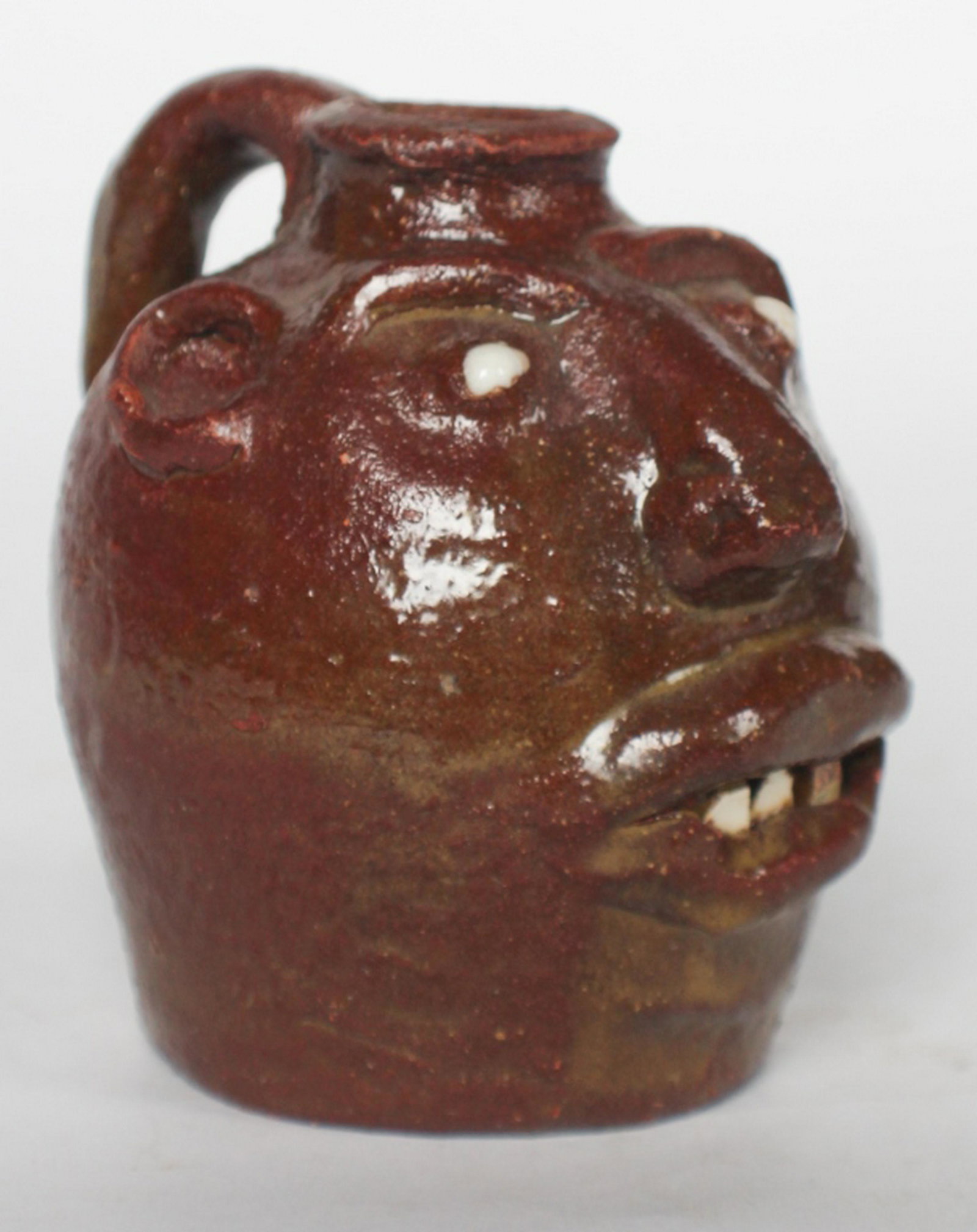 Southern Stoneware Face Jug: Georgia, 20th century by Marie Rogers. An earlier form for this potter having china teeth and eyes. Signed at the base. Good condition. H4 1/2" Sold from the private collection of a Charleston family.