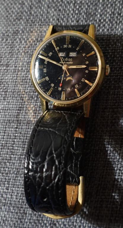 Vintage Mens Zodiac Automatic Moon Face WristWatch: Mid 20th century. Having a black dial with yellow gold accents. The watch would benefit from a cleaning. All jewelry lots in this sale have been professionally examined by a jeweler and authenticated.