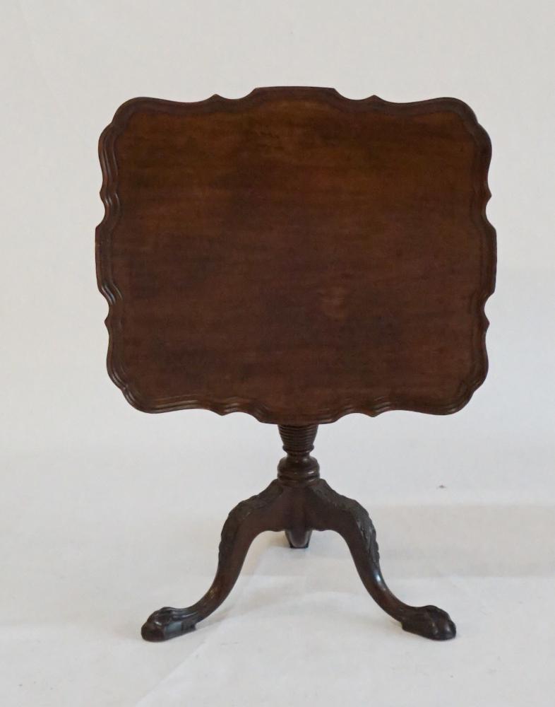 Irish Chippendale Style Pie Crust Tilt TopTeaTable: Early 20th century. Handsomely crafted mahogany piece. The square top with shaped and raised edge atop hinged lower turned wood shaft emitting three nicely carved acanthus legs ending in ball and claw