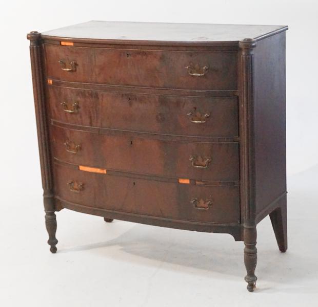 New England Federal Mahogany Chest of Drawers: Circa 1825. Having a bow front top and case with rosettes at each corner of the top and tricorner columns reeded down each side centered by four slightly graduated drawers all atop a tall turned wood 