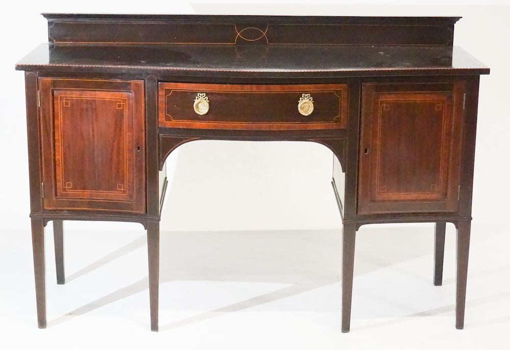 English Edwardian Inlaid Mahogany Sideboard: Circa 1890. Having a backsplash which is nicely banded above serpentine top with satinwood inlaid edge above single drawer at the center flanked by hinged doors at left and right all resting on six ni