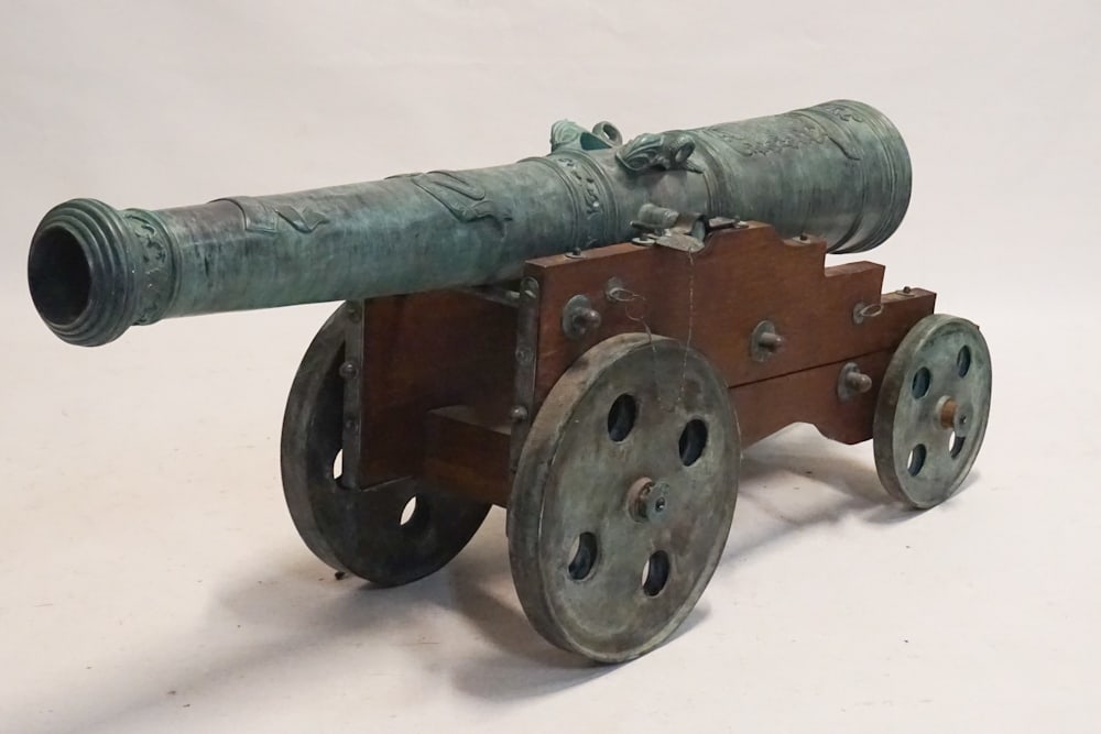 Vintage Hungarian Ornamental Cannon: 20th century. Cannon having a nice patina with classical style mounts all atop cart with four wheels for easy movement. L70" H28" W17" Sold from the collection of a South Carolina gentleman diplomat.