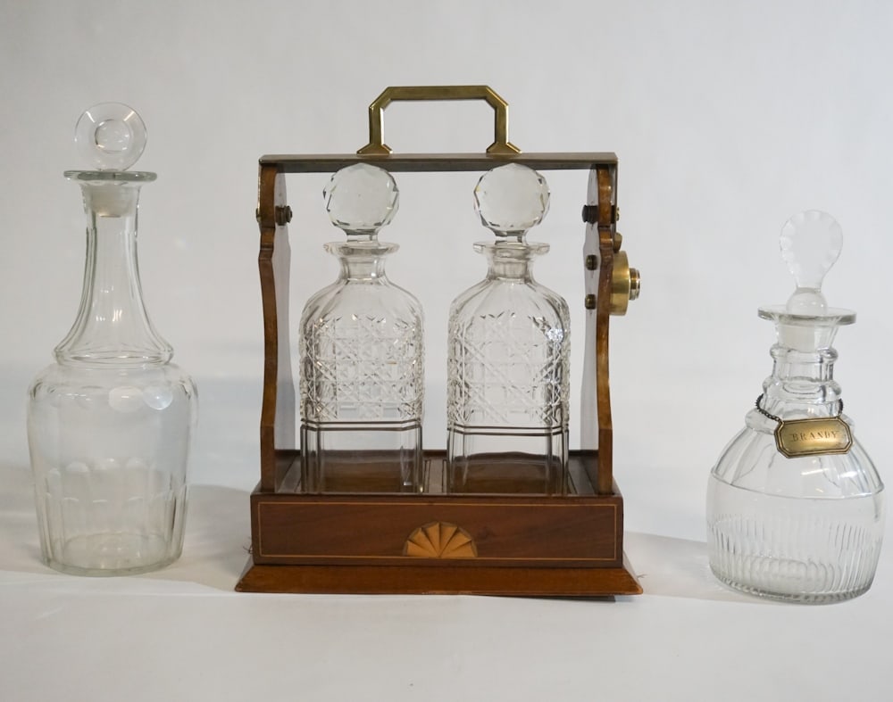 Antique English Edwardian Tantalus & Decanters: Circa 1900. Having a brass handle which locks in place to house the three decanters above lower case having been very nicely inlaid with satinwood. The tantalus is accompanied by two extra decanters h