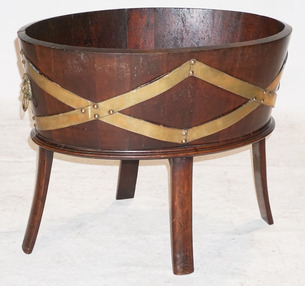 English George III Style Mahogany Wine Cooler: Likely circa 1900 Edwardian period. The piece having barrel style brass bound body with handsome lion head handles at each end resting atop four flared legs. H20 1/4" W25 1/2" D18" Sold from the colle